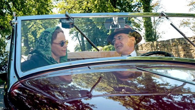 Actress Sofia Helin as Crown Princess Martha in a car with actor Kyle Mclaughlin as Franklin Roosevelt in Atlantic Crossing.