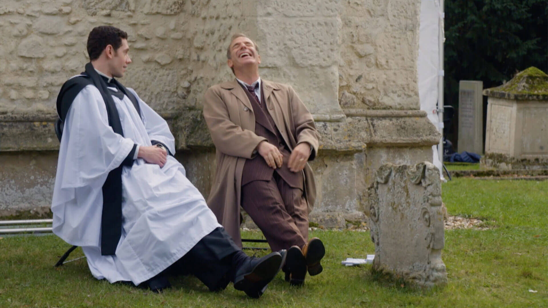 Actors Tom Brittney and Robson Green share a laugh on the set of MASTERPIECE's mystery series Grantchester.